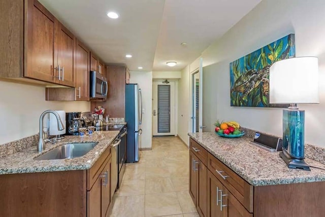 kitchen with sink, appliances with stainless steel finishes, and light stone counters