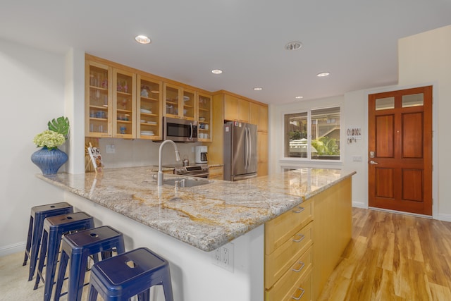 kitchen featuring kitchen peninsula, appliances with stainless steel finishes, sink, and a breakfast bar