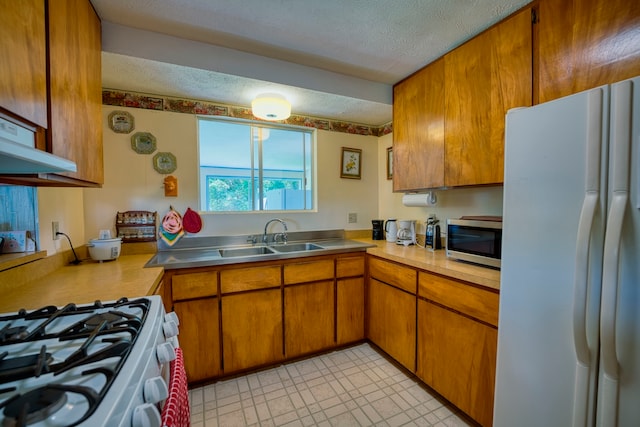 kitchen featuring sink, white appliances, and a textured ceiling