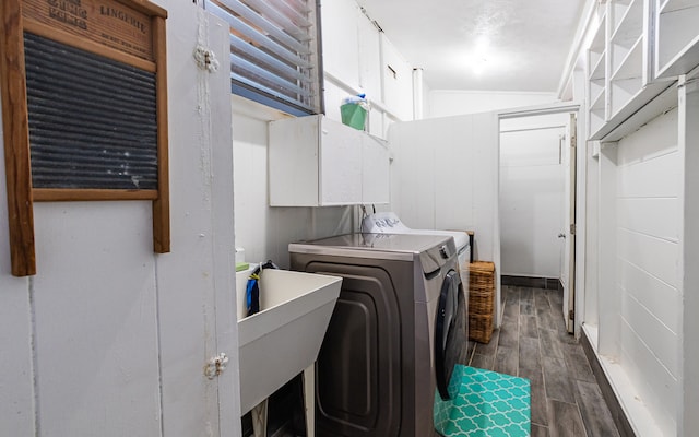 laundry area featuring dark wood-type flooring, separate washer and dryer, cabinets, and sink