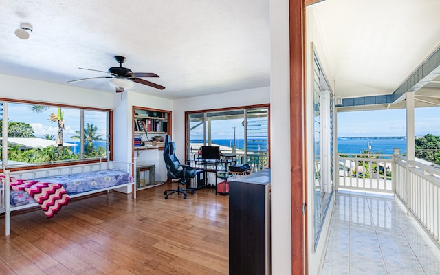 interior space with a water view, ceiling fan, and light hardwood / wood-style flooring