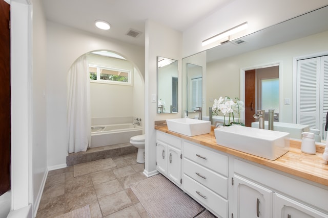 bathroom with vanity, a tub, and toilet