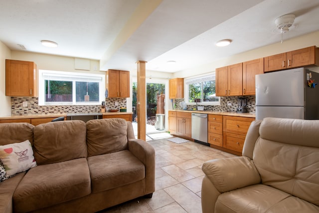 kitchen featuring tasteful backsplash, light tile patterned flooring, decorative columns, ceiling fan, and stainless steel appliances