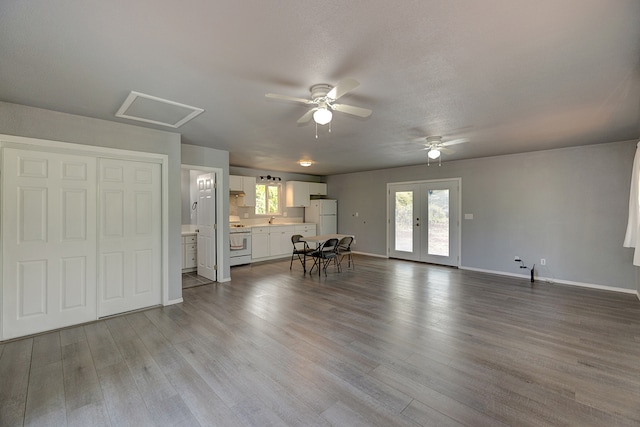 unfurnished living room featuring sink, ceiling fan, french doors, and light hardwood / wood-style flooring