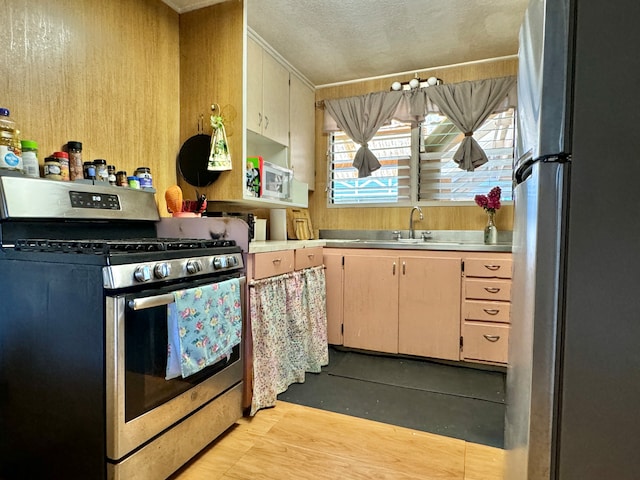 kitchen featuring stainless steel appliances, sink, crown molding, light hardwood / wood-style flooring, and a textured ceiling