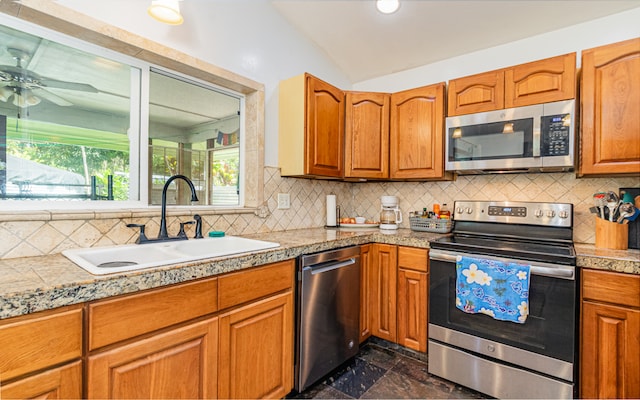 kitchen featuring ceiling fan, sink, stainless steel appliances, vaulted ceiling, and decorative backsplash