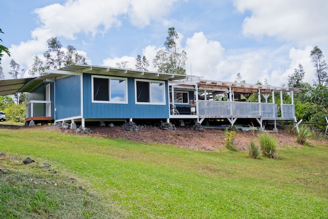 rear view of property featuring a yard, a pergola, and a deck