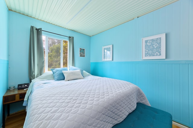 bedroom with hardwood / wood-style flooring and wooden walls