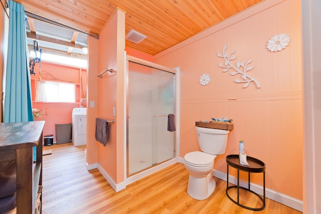 bathroom featuring washer / dryer, vanity, wood-type flooring, a shower with door, and toilet