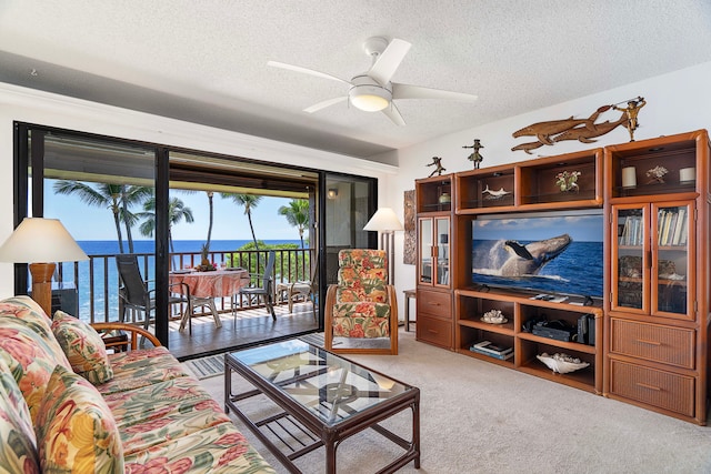 carpeted living room featuring a textured ceiling, a water view, and ceiling fan