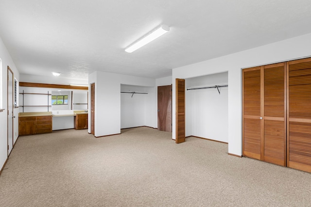 unfurnished bedroom featuring connected bathroom, multiple closets, and light carpet