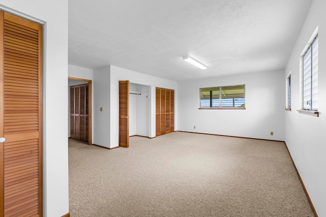 empty room with a textured ceiling and light carpet