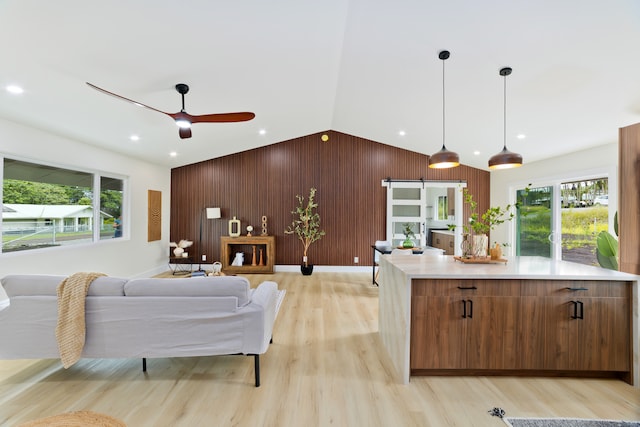 interior space with lofted ceiling, ceiling fan, light wood-type flooring, and wood walls