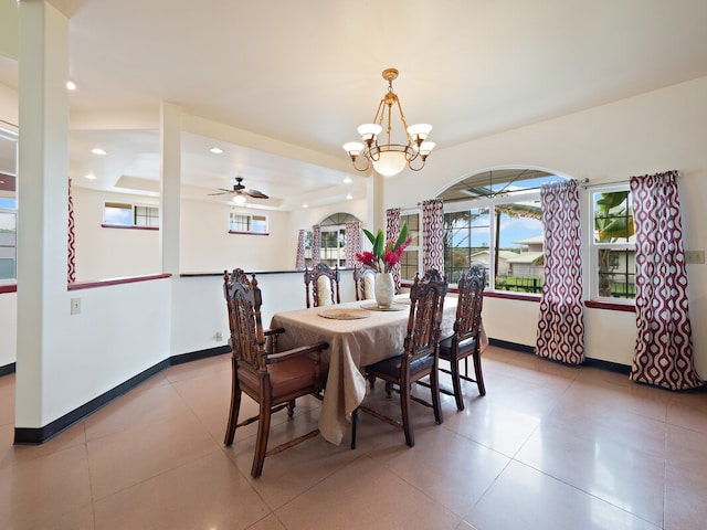 dining space featuring a raised ceiling and ceiling fan with notable chandelier