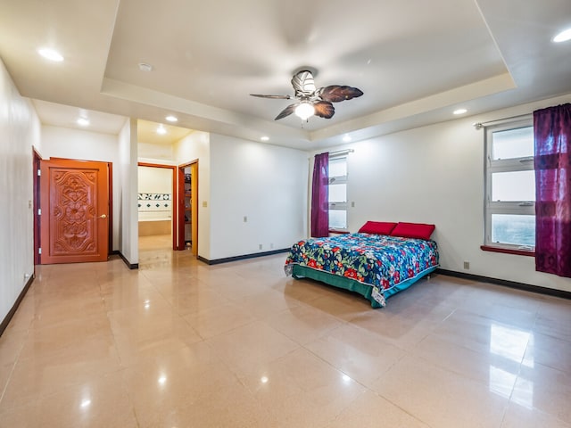 tiled bedroom featuring ensuite bath, ceiling fan, and a raised ceiling