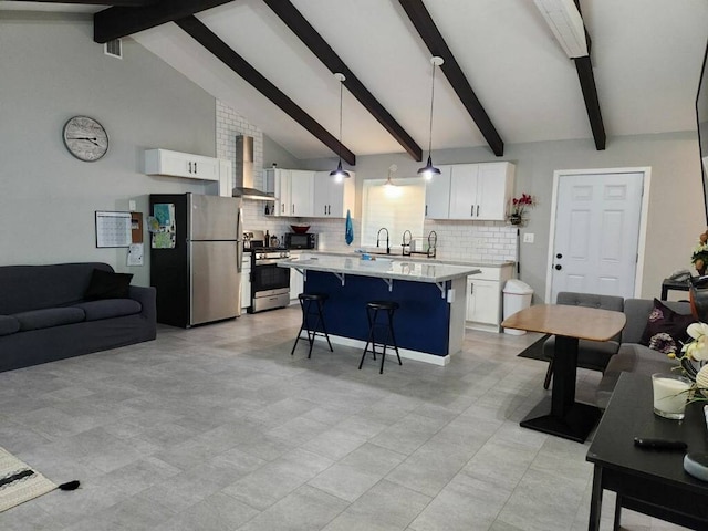 kitchen featuring stainless steel appliances, hanging light fixtures, wall chimney exhaust hood, and white cabinetry