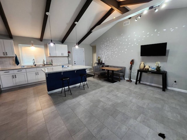 kitchen featuring lofted ceiling with beams, a kitchen island, white cabinetry, decorative light fixtures, and a kitchen breakfast bar