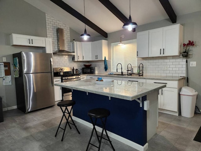 kitchen with white cabinets, appliances with stainless steel finishes, hanging light fixtures, and wall chimney exhaust hood