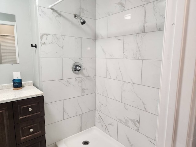 bathroom with a tile shower and vanity