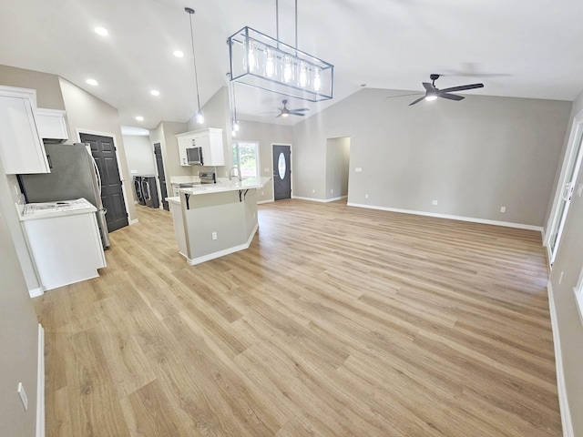 kitchen with open floor plan, ceiling fan, light countertops, white cabinets, and vaulted ceiling