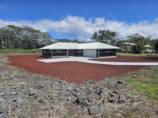 exterior space with an attached garage, driveway, and metal roof