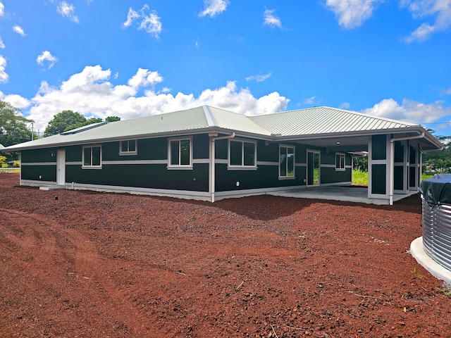 back of house featuring a patio, an attached carport, and metal roof