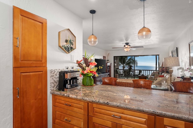 kitchen featuring light stone countertops, decorative light fixtures, and ceiling fan