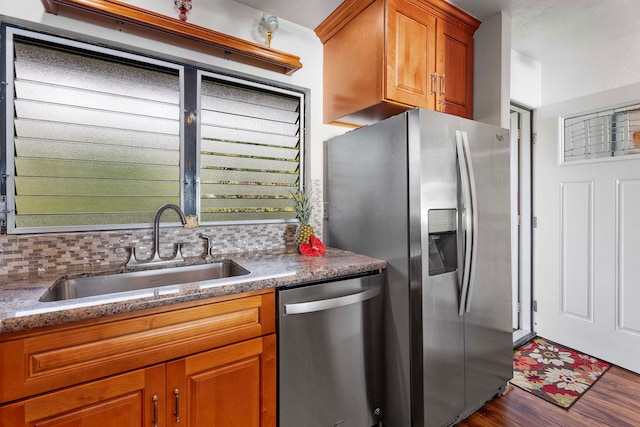 kitchen featuring appliances with stainless steel finishes, decorative backsplash, sink, and wood-type flooring