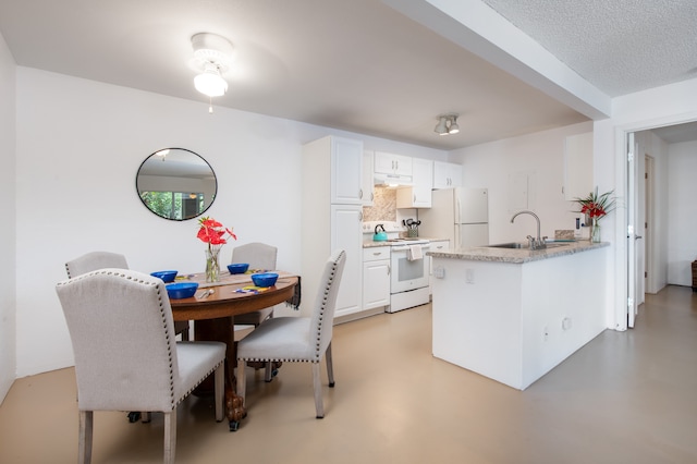 kitchen with white appliances, sink, a textured ceiling, kitchen peninsula, and white cabinets