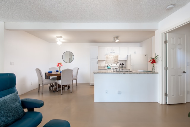 kitchen with white fridge, a textured ceiling, and white cabinets