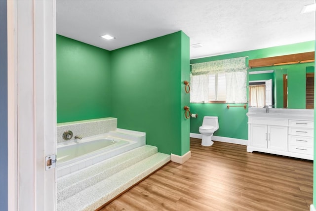 bathroom featuring a textured ceiling, toilet, a bathtub, vanity, and hardwood / wood-style flooring