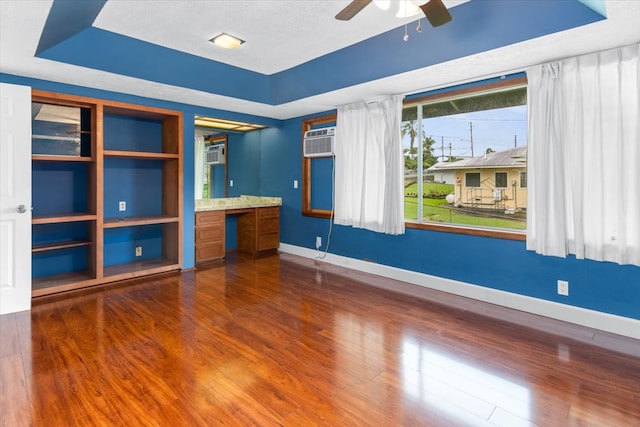 interior space featuring dark hardwood / wood-style floors, ceiling fan, and a tray ceiling