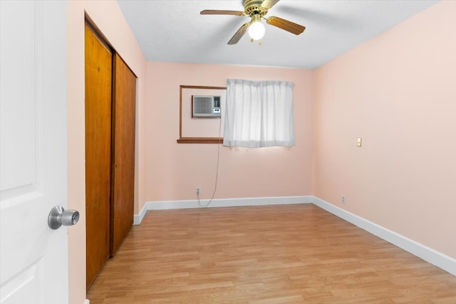 unfurnished bedroom with a wall mounted air conditioner, light wood-type flooring, a closet, and ceiling fan