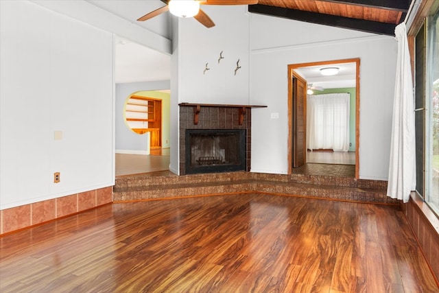 unfurnished living room with a tile fireplace, a healthy amount of sunlight, lofted ceiling with beams, and hardwood / wood-style flooring