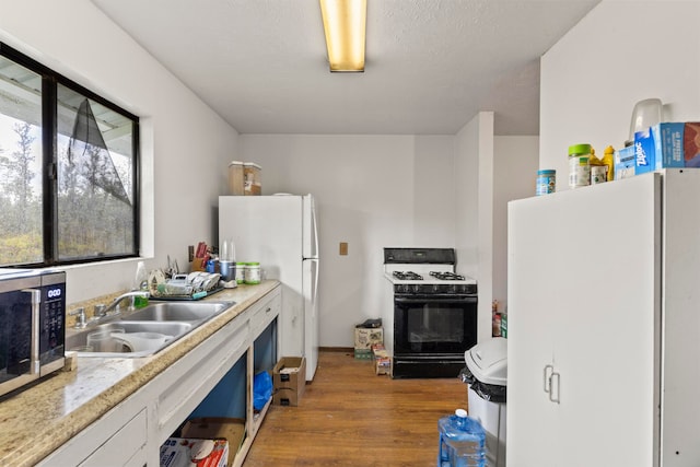 kitchen featuring white fridge, hardwood / wood-style flooring, sink, and black gas stove