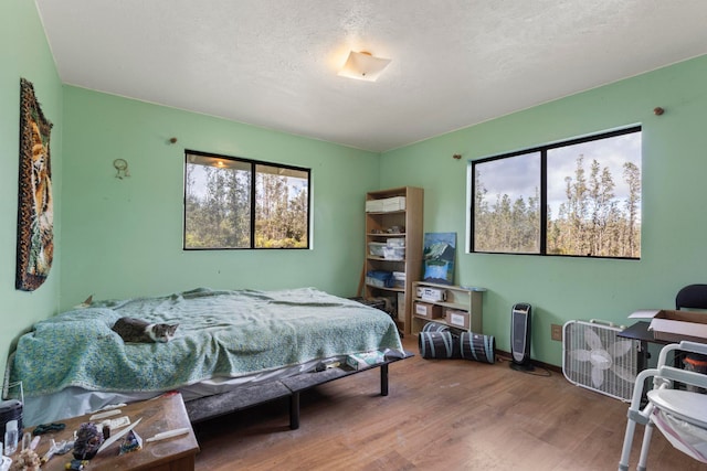 bedroom featuring multiple windows, hardwood / wood-style floors, and a textured ceiling