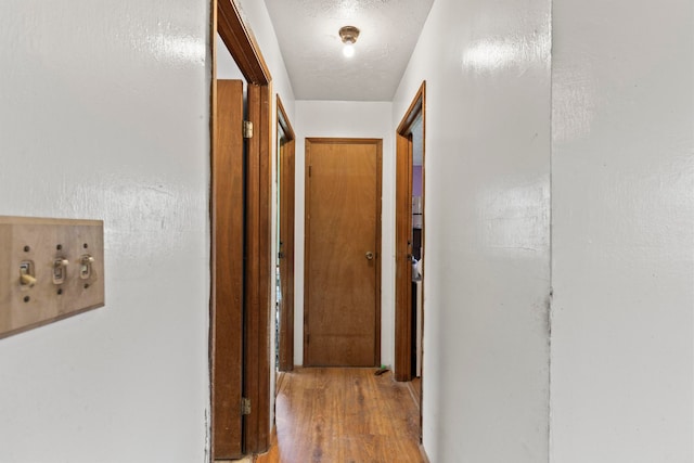 corridor with light hardwood / wood-style flooring and a textured ceiling