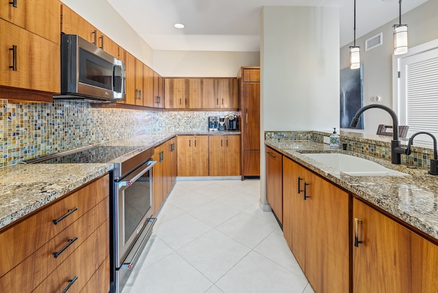 kitchen featuring decorative light fixtures, appliances with stainless steel finishes, sink, and light stone countertops