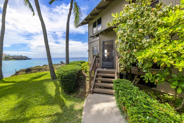 view of exterior entry featuring a water view and a yard