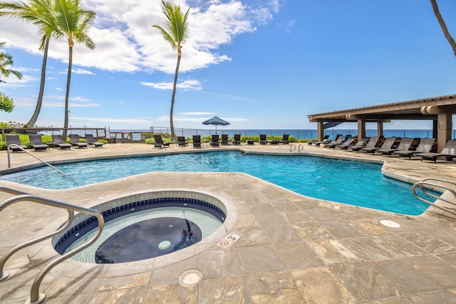 view of pool featuring a water view, a patio, and a hot tub