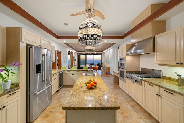 kitchen with light stone counters, wall chimney exhaust hood, a center island, and stainless steel appliances