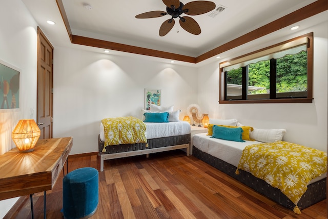 bedroom featuring ceiling fan, hardwood / wood-style flooring, and a raised ceiling