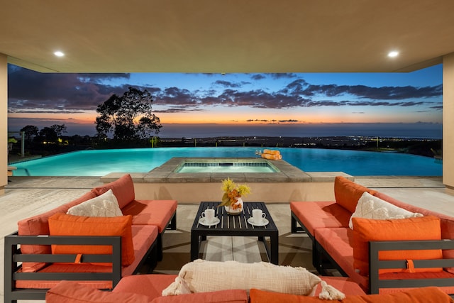 pool at dusk with an outdoor living space, a water view, an in ground hot tub, and a patio area