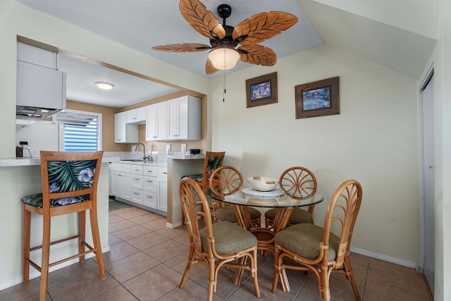 dining space with light tile patterned flooring, lofted ceiling, sink, and ceiling fan