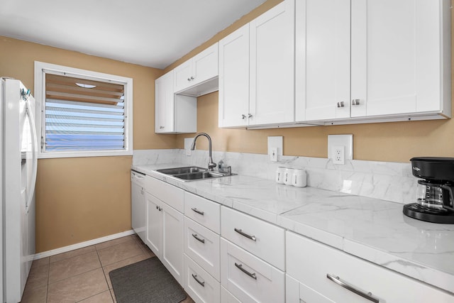 kitchen with light stone countertops, white appliances, sink, white cabinetry, and light tile patterned floors