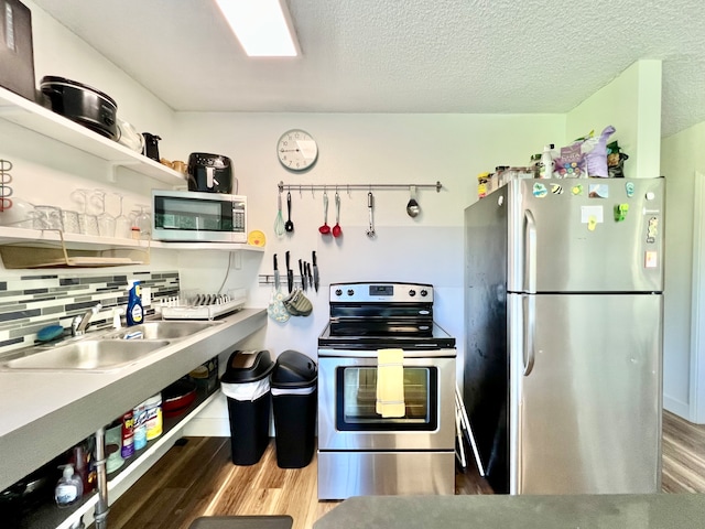 kitchen with a textured ceiling, sink, hardwood / wood-style flooring, and stainless steel appliances