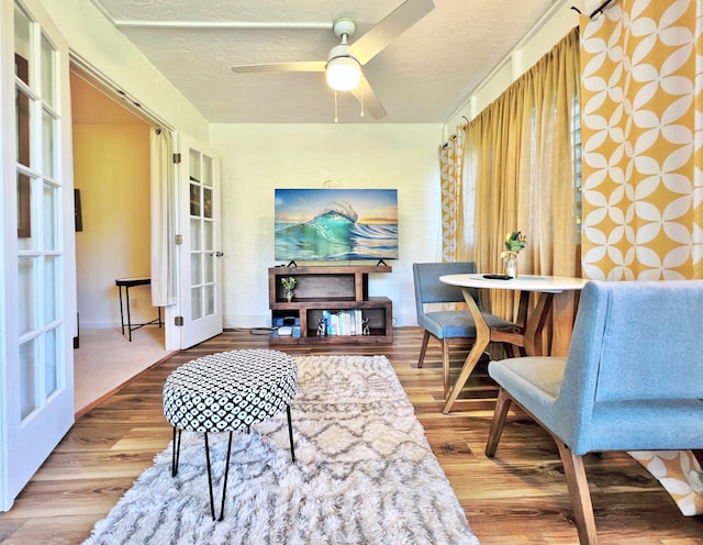 living area featuring a textured ceiling, french doors, wood-type flooring, and ceiling fan