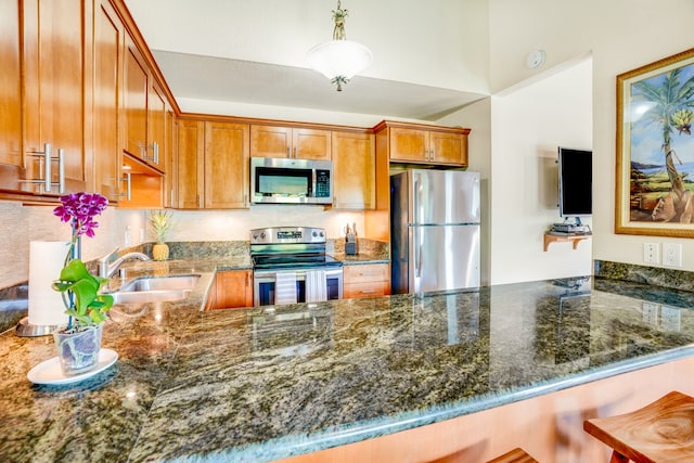 kitchen featuring kitchen peninsula, stainless steel appliances, sink, a kitchen bar, and decorative light fixtures