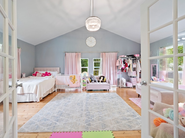 bedroom featuring light hardwood / wood-style flooring, french doors, and high vaulted ceiling