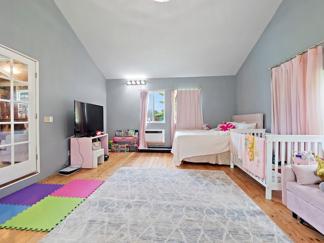 bedroom featuring lofted ceiling, a wall unit AC, and wood-type flooring